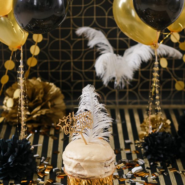 Birthday party cake with golden and black decor various balloons. Happy birthday sign.
